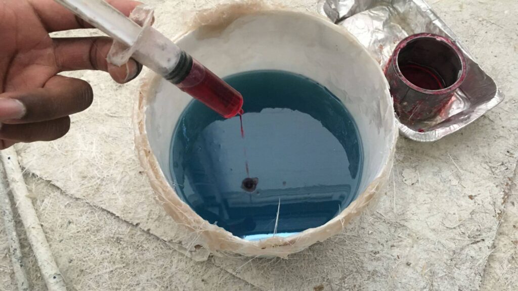 Close up hand putting catalyst inside fiberglass resin