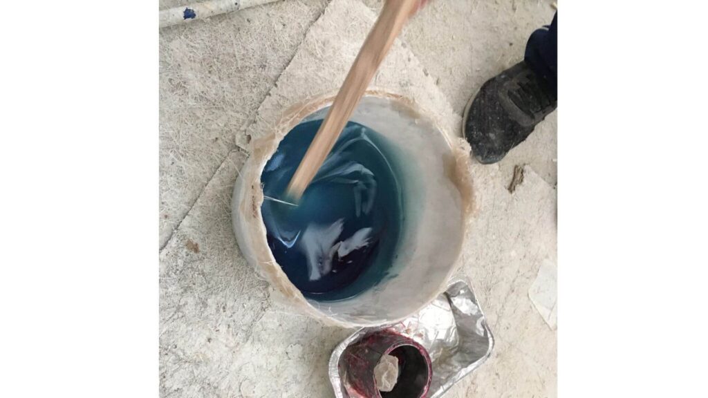 Repairing a large hole in a fiberglass hole - someone mixing resin and catalyst