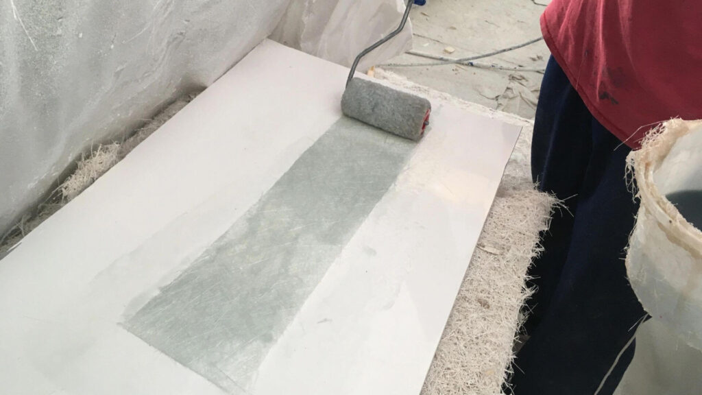 someone laminating a fiberglass mat with resin