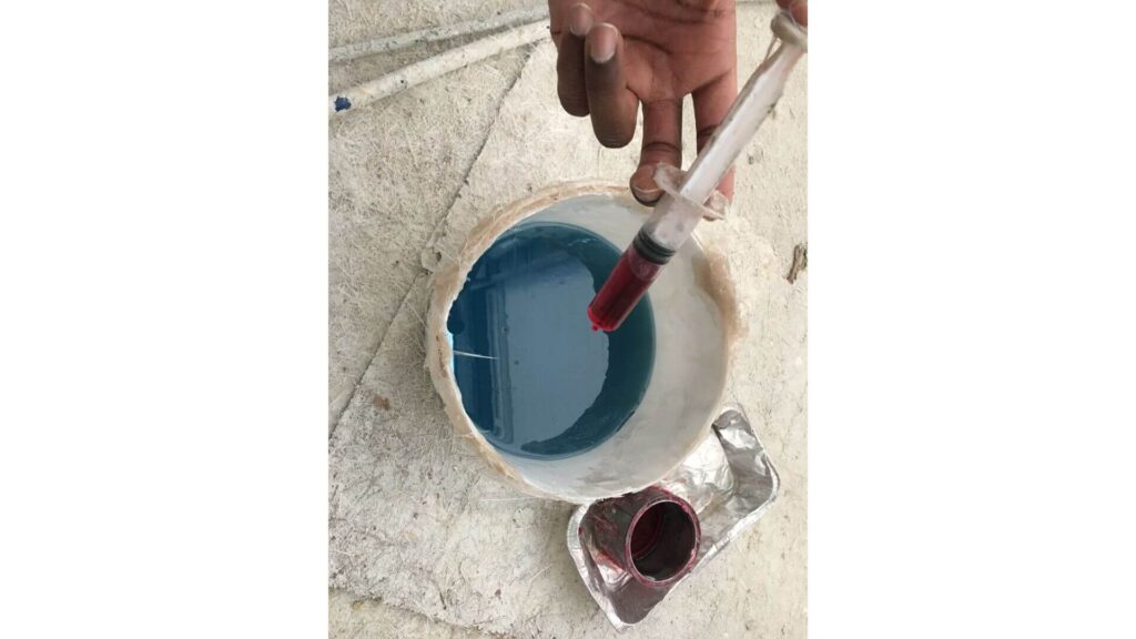 close up hand putting catalyst in a bucket of polyester resin